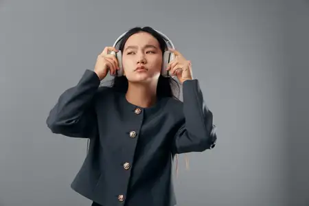 Женщина с длинными волосами в наушниках наслаждается звуком с закрытыми глазами в студии