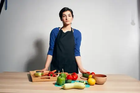 Женщина в черном фартуке готовит здоровую пищу на изолированном фоне