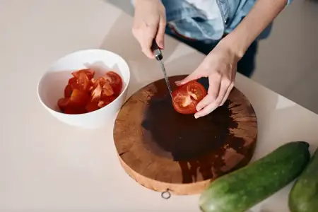 Свежий полезный салат: женщина-шеф-повар готовит вкусное вегетарианское блюдо на деревянной разделочной доске