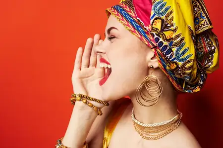 Веселая женщина этнической внешности с разноцветным тюрбаном на красном фоне