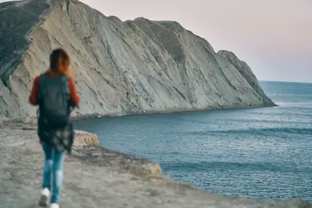 Женщина в горах у моря, на заднем плане скалы, природа, свежий воздух