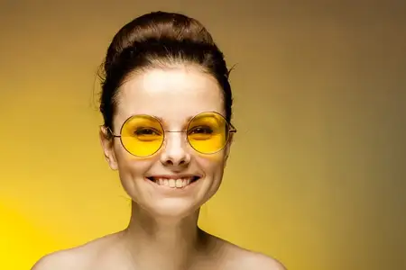 Веселая женщина в желтых очках, улыбка, обнаженные плечи, обрезанный вид