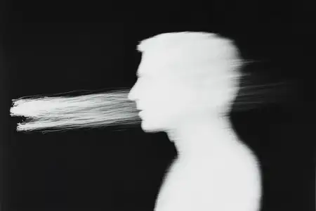 Это черно-белое художественное изображение запечатлевает размытый профиль мужчины, вызывая эмоции замешательства и самоанализа, идеально подходит для тем психического здоровья и саморефлексии