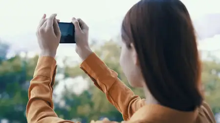 Женщина с телефоном в руках фотографирует природу на открытом воздухе