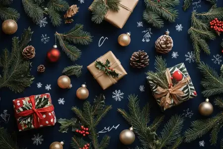 Праздничная рождественская flat lay-композиция с искусно упакованными подарками, золотыми украшениями, сосновыми шишками и свежей зеленью на насыщенном синем фоне, идеальная для праздничных торжеств