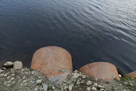 На берегу озера прозрачная вода омывает камни и гальку у кромки воды