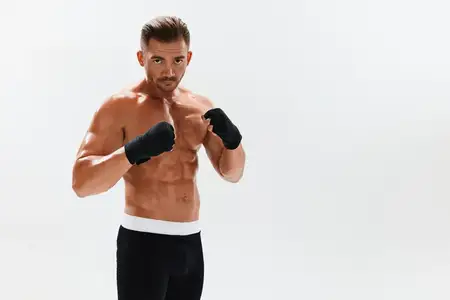 Спортивный мужчина, культурист, позирует в боксерских перчатках с обнаженным торсом и прессом в полный рост на фоне, бокс и боевые искусства