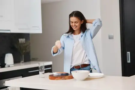 Женщина стоит на кухне с миской еды и тарелкой перед собой, готовя вкусное блюдо