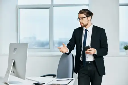 Мужчина-менеджер в деловом костюме работает в офисе с телефоном и современными технологиями