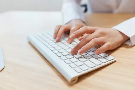 Крупным планом руки бизнесвумен, журналистки, офисной работницы, фрилансера печатают отчет, работая с документами на клавиатуре