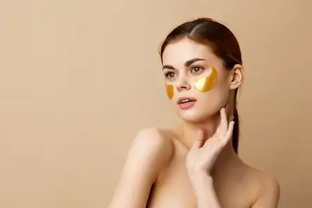 Портрет женщины с золотыми патчами, чистая кожа, улыбка и поза на изолированном фоне