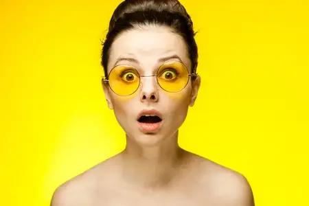 Привлекательная брюнетка в жёлтых очках с обнажёнными плечами в студии