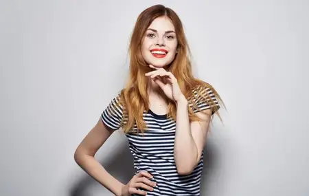 Весёлая симпатичная женщина с очаровательной причёской улыбается на фоне косметики и предметов роскоши