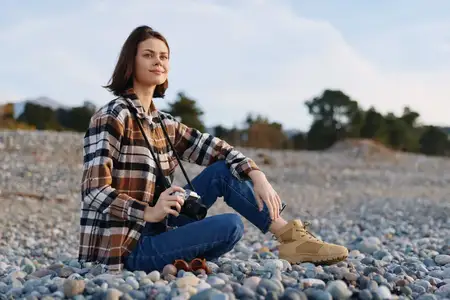 Уличный портрет женщины с камерой на галечном пляже