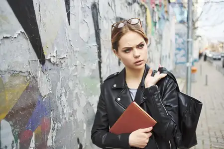 Счастливая женщина читает книгу на улице рядом с граффити на стене