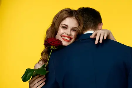 Влюбленная пара — мужчина и женщина в классических костюмах и красном платье с красной розой