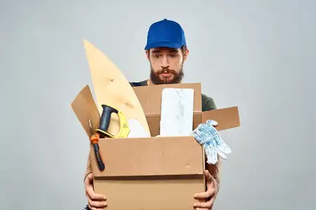 Мужчина в рабочей форме с коробкой в руках, инструменты, образ жизни, светлый фон