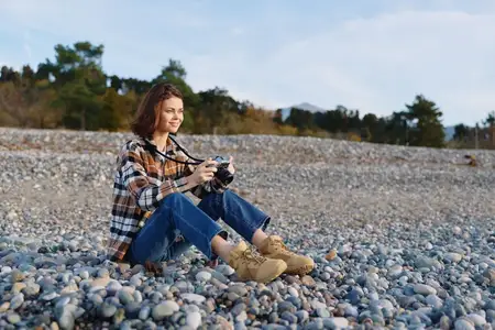 Фотограф-любитель на каменистом берегу снимает текстуры и свет ручной камерой
