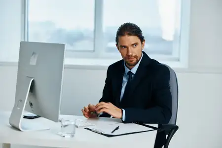 Мужчина-менеджер работает перед компьютером с документами, демонстрируя определённый образ жизни