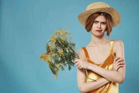 Женщина в золотистом платье с букетом цветов мимозы на празднике