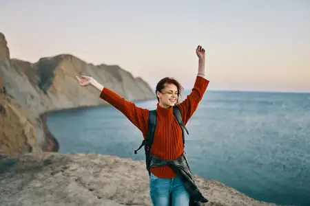 Счастливое путешествие с поднятыми вверх руками в горах у моря на природе, обрезанный вид