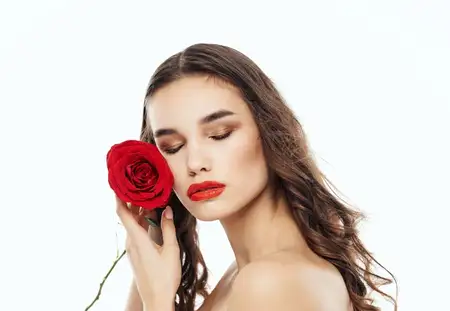 Женщина с красным цветком возле лица, чистая кожа, косметология, модель