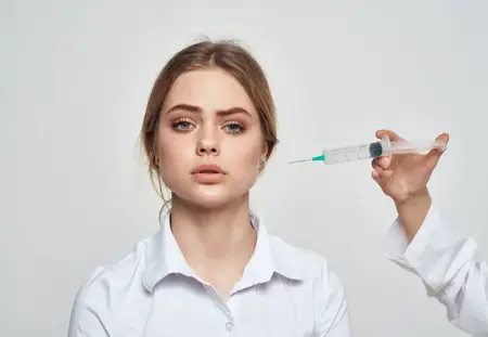 Шприц с жидкостью и пациентка в белой футболке, у которой проблемы со здоровьем