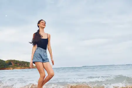 Женщина идёт по пляжу на закате