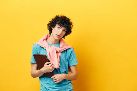Студент с книгой в колледже учится в розовой куртке на изолированном фоне
