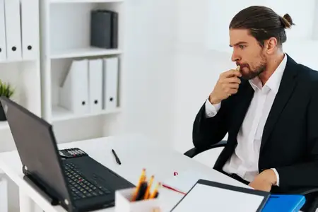 Менеджер работает за ноутбуком на рабочем столе в офисе, что отражает офисный образ жизни