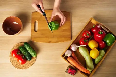 Домохозяйка готовит здоровую пищу, используя разделочную доску