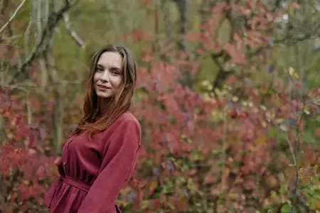 Сцена предлагает тихое, искреннее настроение повседневной жизни, подчеркивая честность и уверенность, когда листья светятся, а ветер шевелит волосы в спокойный, аутентичный момент