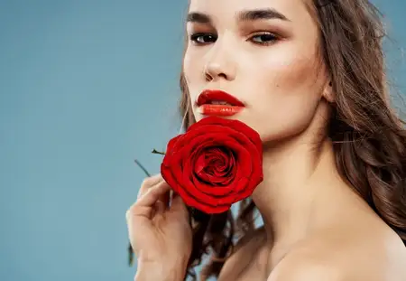 Сексуальная женщина с обнаженными плечами и красным цветком возле лица