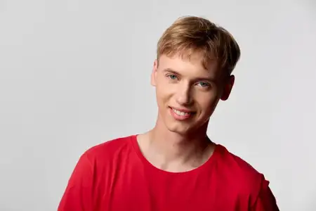 Яркий мужчина-модель с дружелюбной улыбкой в красной футболке на чистом фоне, подходит для брендинга, социальных сетей и маркетинговых визуалов, делающих акцент на доступности, молодости и…