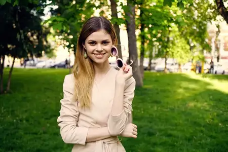 Симпатичная женщина отдыхает на фоне зелёных деревьев в парке