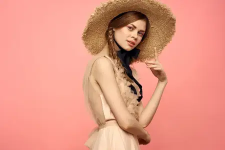 Романтичная девушка с косичками и в соломенной шляпе улыбается