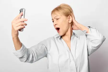 Женщина в позе для селфи на смартфон, кричит от дискомфорта в ушах, руки на ушах, шум общения, разочарование, перегрузка, стрессовые эмоции, удивление и настороженная реакция, концепция выгорания и…