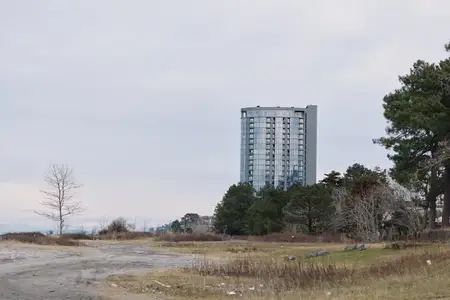 Высотное здание, пейзаж, поле, далёкий горизонт города и одинокая местность создают тихую сцену городского присутствия в широком природном окружении