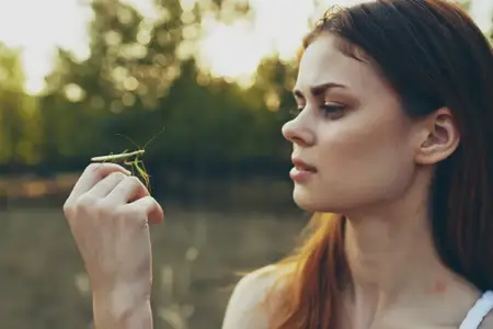 Женщина с насекомым на руке — богомолом, на фоне природы, деревьев, лето