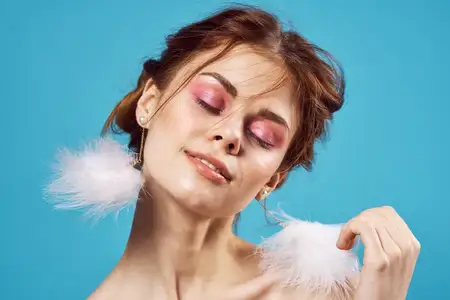 Женщина с обнаженными плечами, пушистыми серьгами и косметикой в модном крупном плане