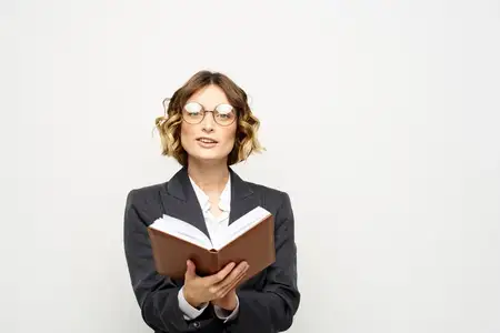 Женщина за работой с книгой в руке на светлом фоне