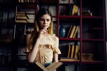 Красивая женщина с книгой в руках отдыхает в кафе