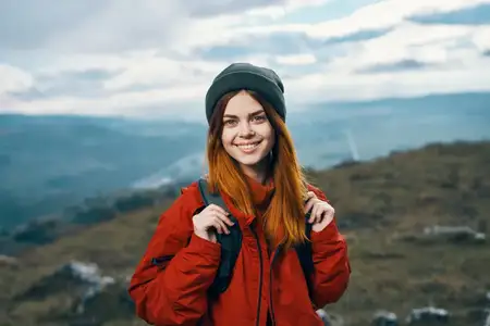 Жизнерадостная женщина-туристка идет в горах, активный отдых, путешествие