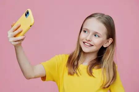 Радостная маленькая девочка делает селфи на свой смартфон