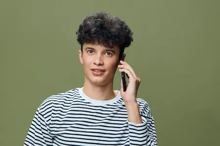 Молодой человек разговаривает по смартфону с внимательным взглядом