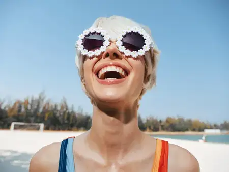 Контекст и настроение: сцена на открытом воздухе передает счастье, молодость и свободу с ясным голубым небом, теплым песком и игривой модой, вдохновляя на жизнерадостное летнее настроение