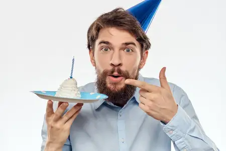 Мужчина в синей рубашке держит тарелку с тортом на светлом фоне