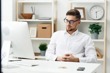 Бизнесмен в очках сидит за столом в офисе, работает, технологии