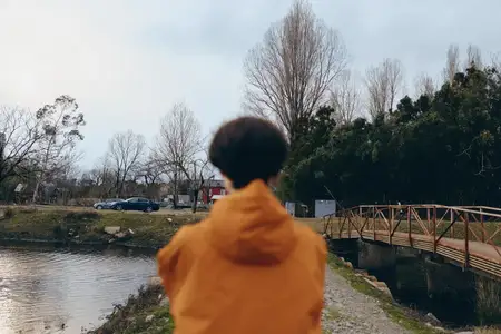 Женщина на улице у реки, озера и моста, вид сзади