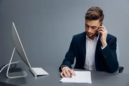 Менеджер сидит за столом перед компьютером с телефонными технологиями